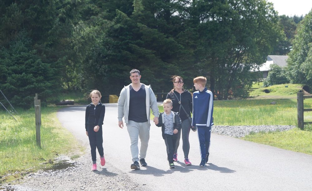 Family of five, enjoying a healthy stroll, which helps to stay well.