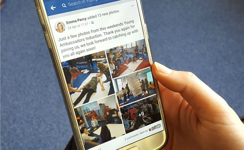 A young adult scrolls through posts in The Brain Tumour Charity's Young Adult Facebook Group using their mobile phone.