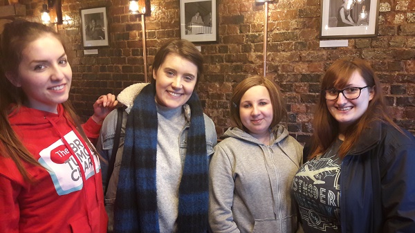 Four casually-dressed young adults stand together, smiling at the camera, at one of The Brain Tumour Charity's Young Adult Meet Ups.