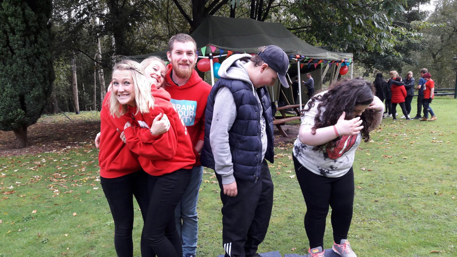 Five young adults mess around in front of the camera at one of The Brain Tumour Charity's Young Adult Meet Ups. They're all smiling and many are dressed in The Brain Tumour Charity branded hoodies.