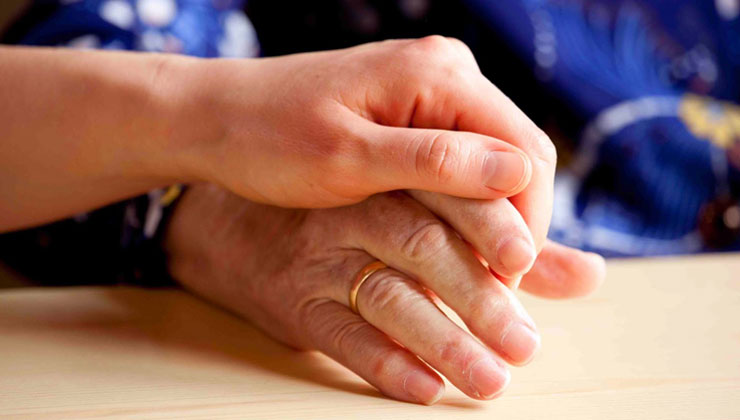 A son reassuring holds his dad's hand as they discuss treatment options following a brian tumour diagnosis.