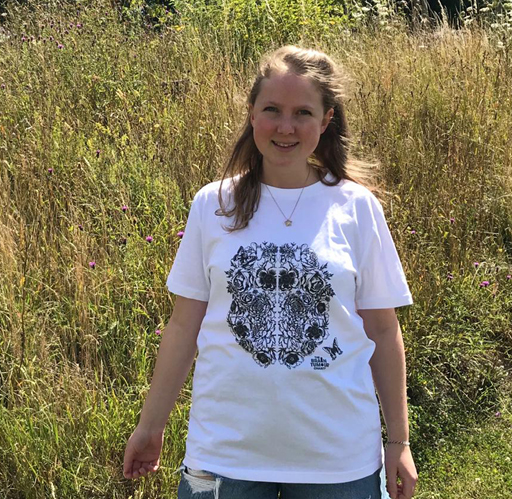 Person standing in a field wearing a black and white Great Minds charity t-shirt