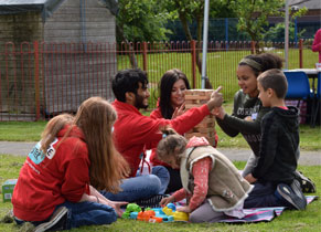 Three young adults in The Brain Tumour Charity hoodies play Giant Jenga in a park with three children.