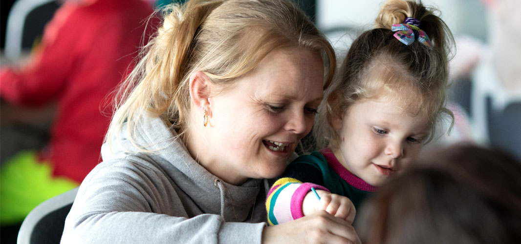 A mother and daughter laughing as they do some colouring in together.