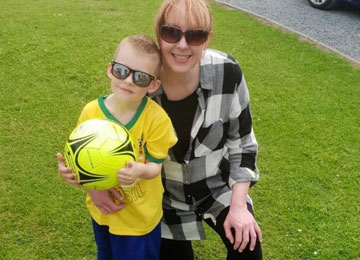 Noah, a six year old boy diagnosed with a rare, low-grade brain tumour poses for a photo with his mother, Donna. Noah looks incredibly cool in his sunglasses and Brazil shirt as he hugs a football.